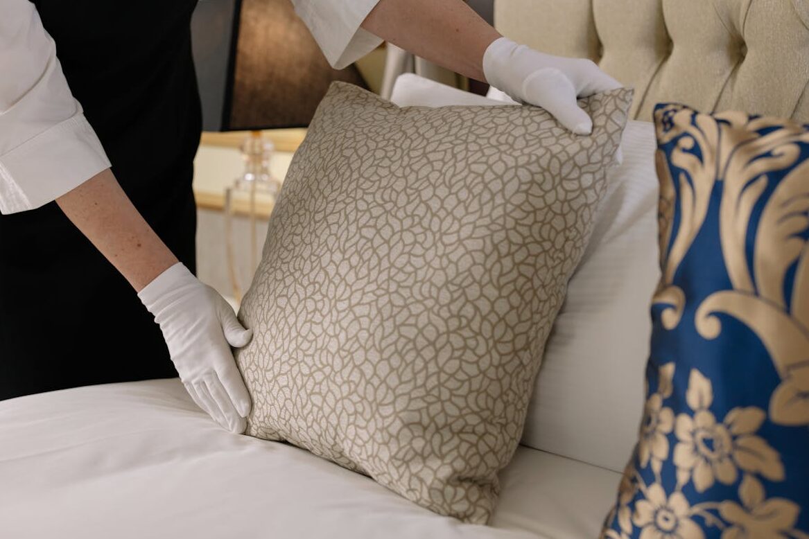 Woman Fixing Pillows on a Bed